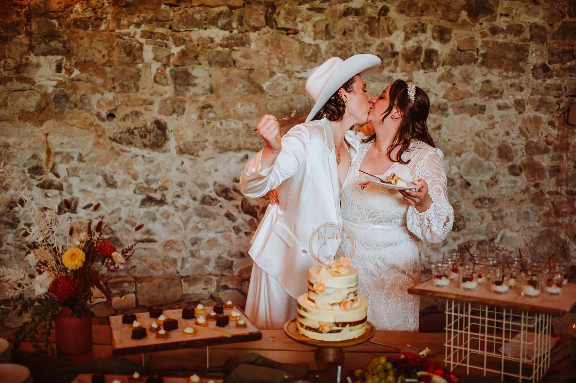 Boda LGTBI: dos novias besándose mientras cortan la tarta de boda en This Must Be The Place, Moià. Piña Colada