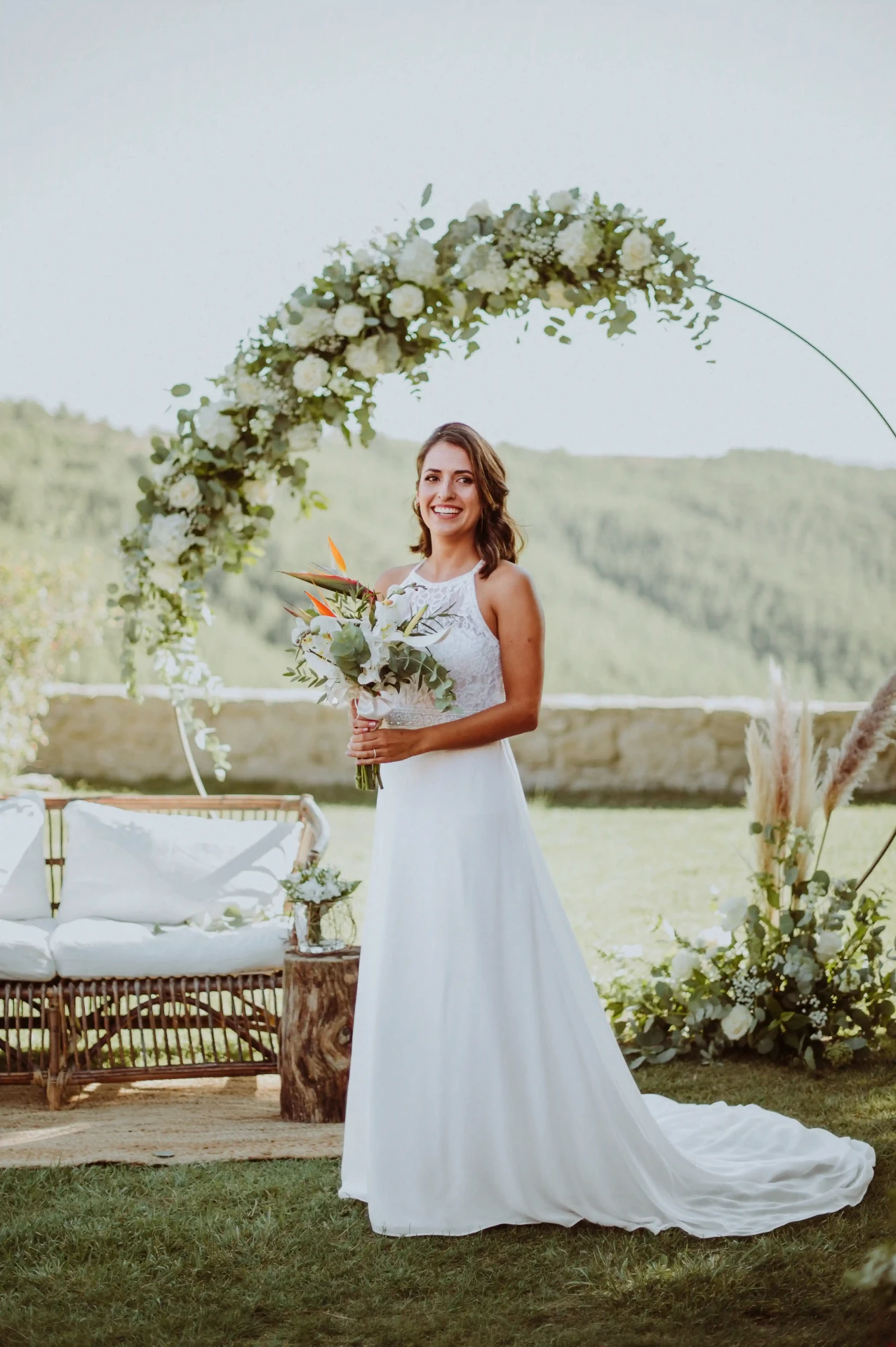 boda LGTBI en Ca n'Alzina — retrato de una de las novias bajo el arco floral con vistas a las montañas