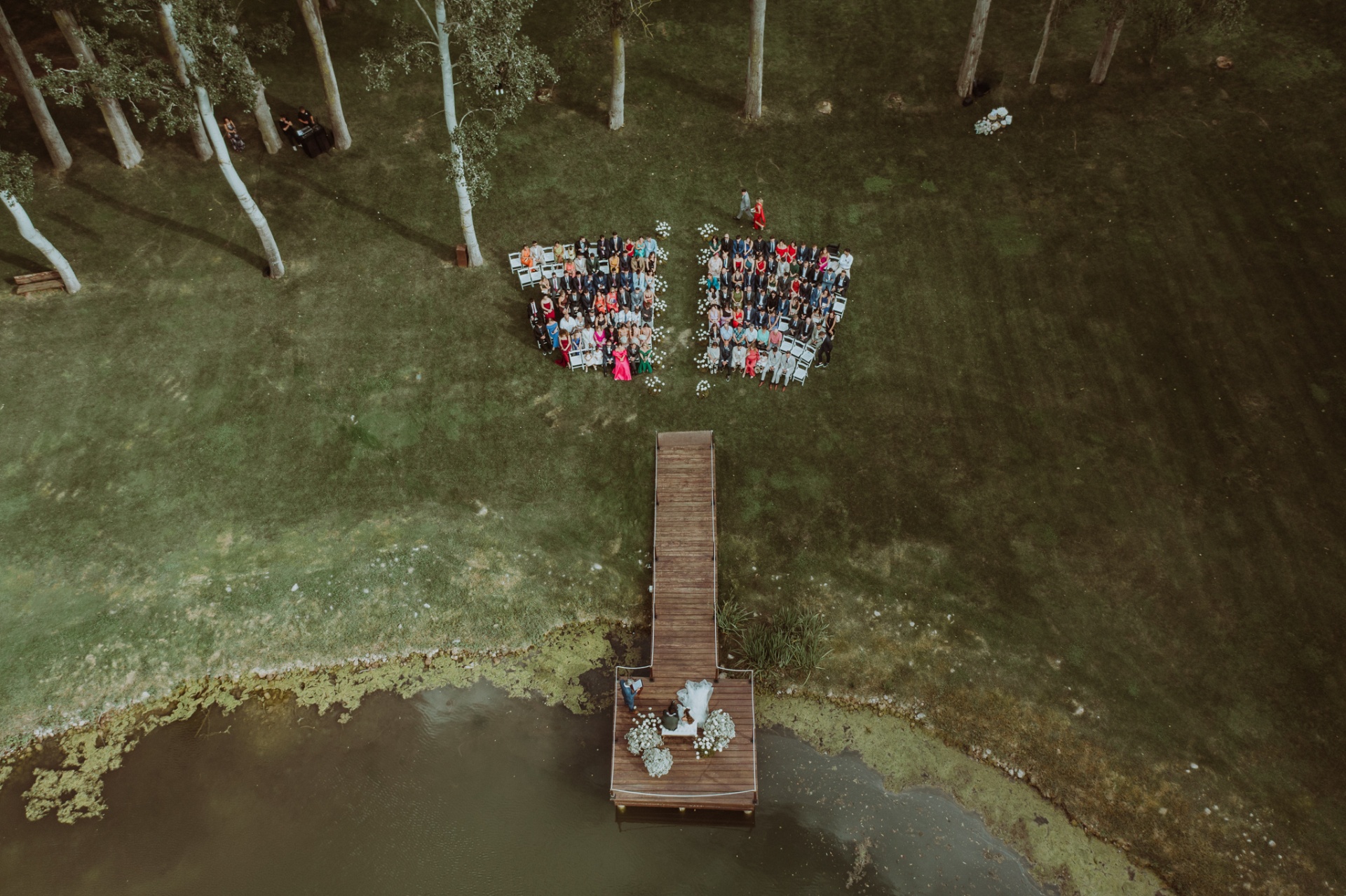 Vista aérea con dron de la ceremonia en el embarcadero de La Farinera con los invitados sentados en el jardín