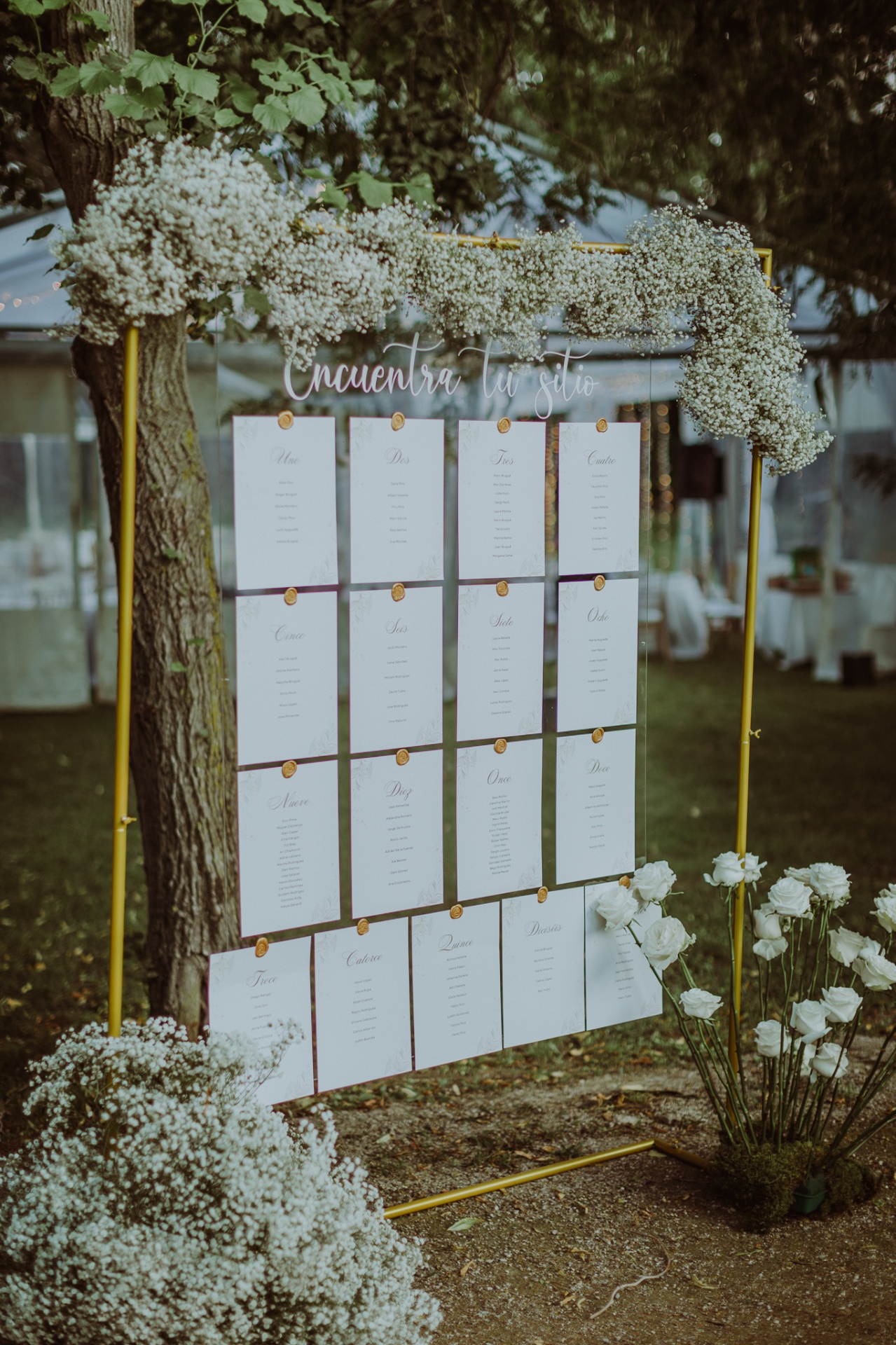 Seating plan elegante con paneles blancos y sellos de lacre dorado decorado con paniculata y rosas blancas