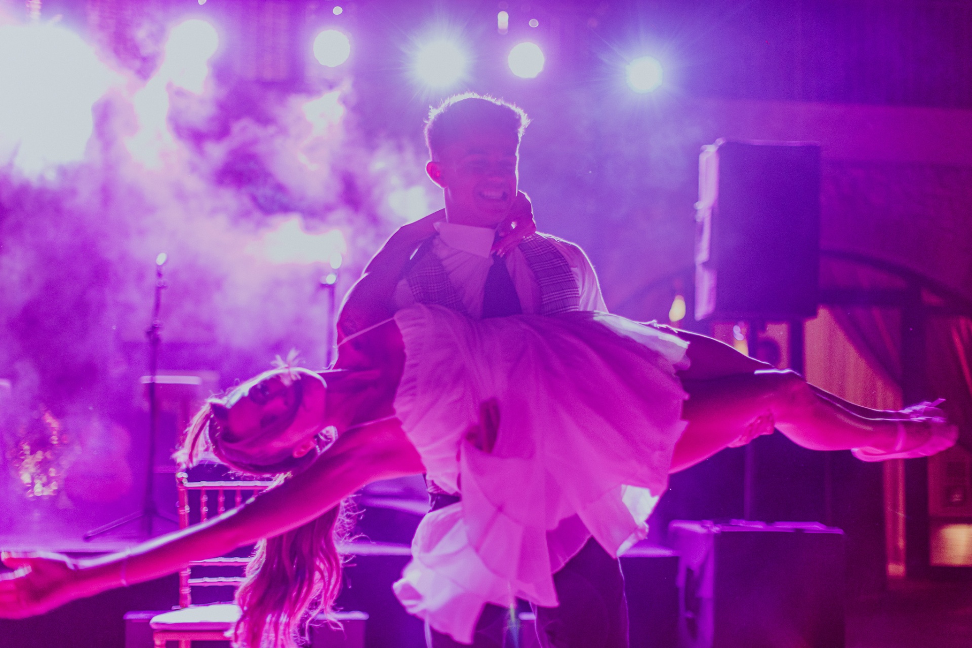 Roger sosteniendo a Alba en brazos durante el primer baile con luces púrpura y humo en la pista