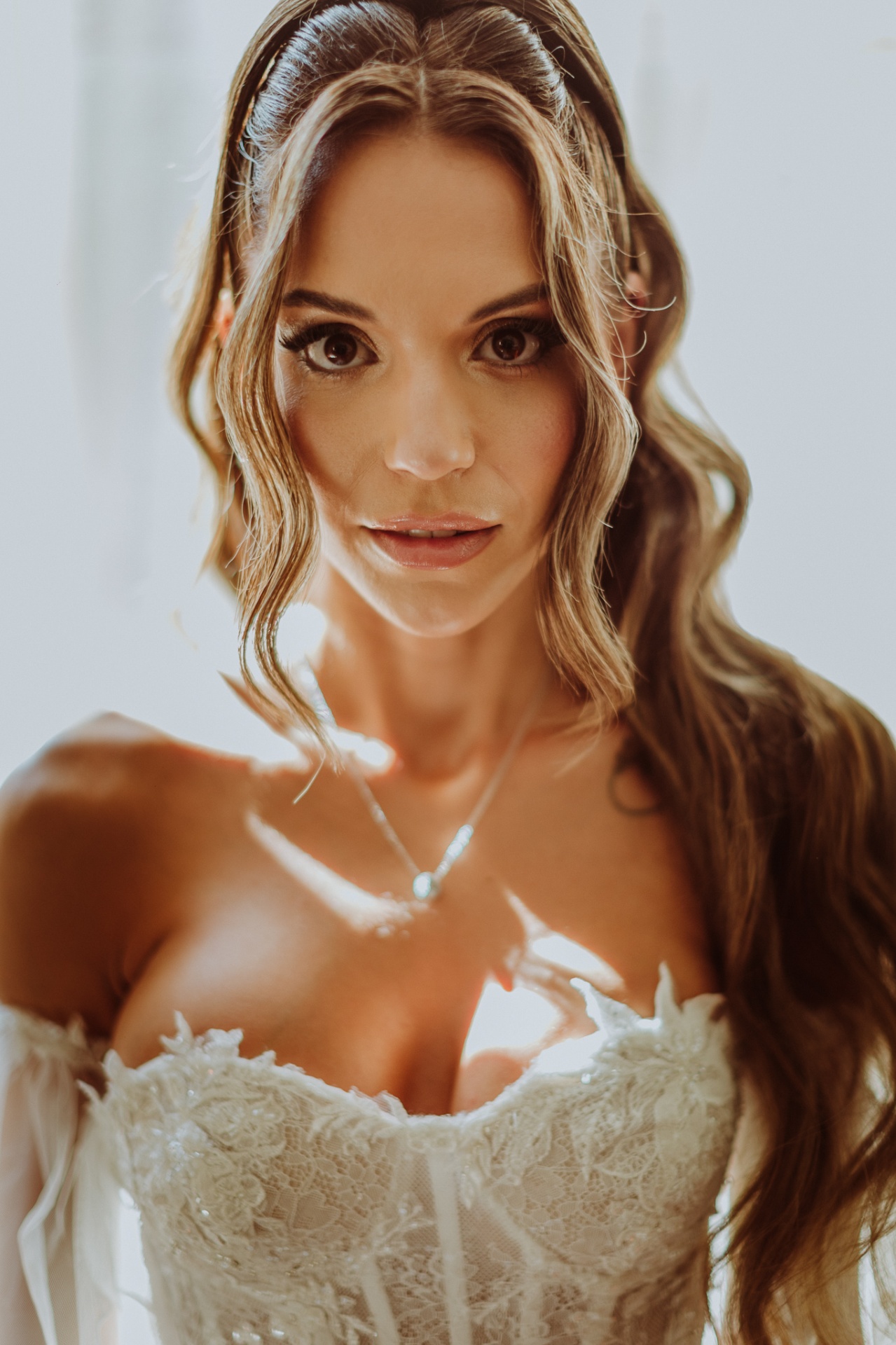 Retrato en primer plano de Alba con maquillaje natural, pelo ondulado y vestido de encaje con escote corazón