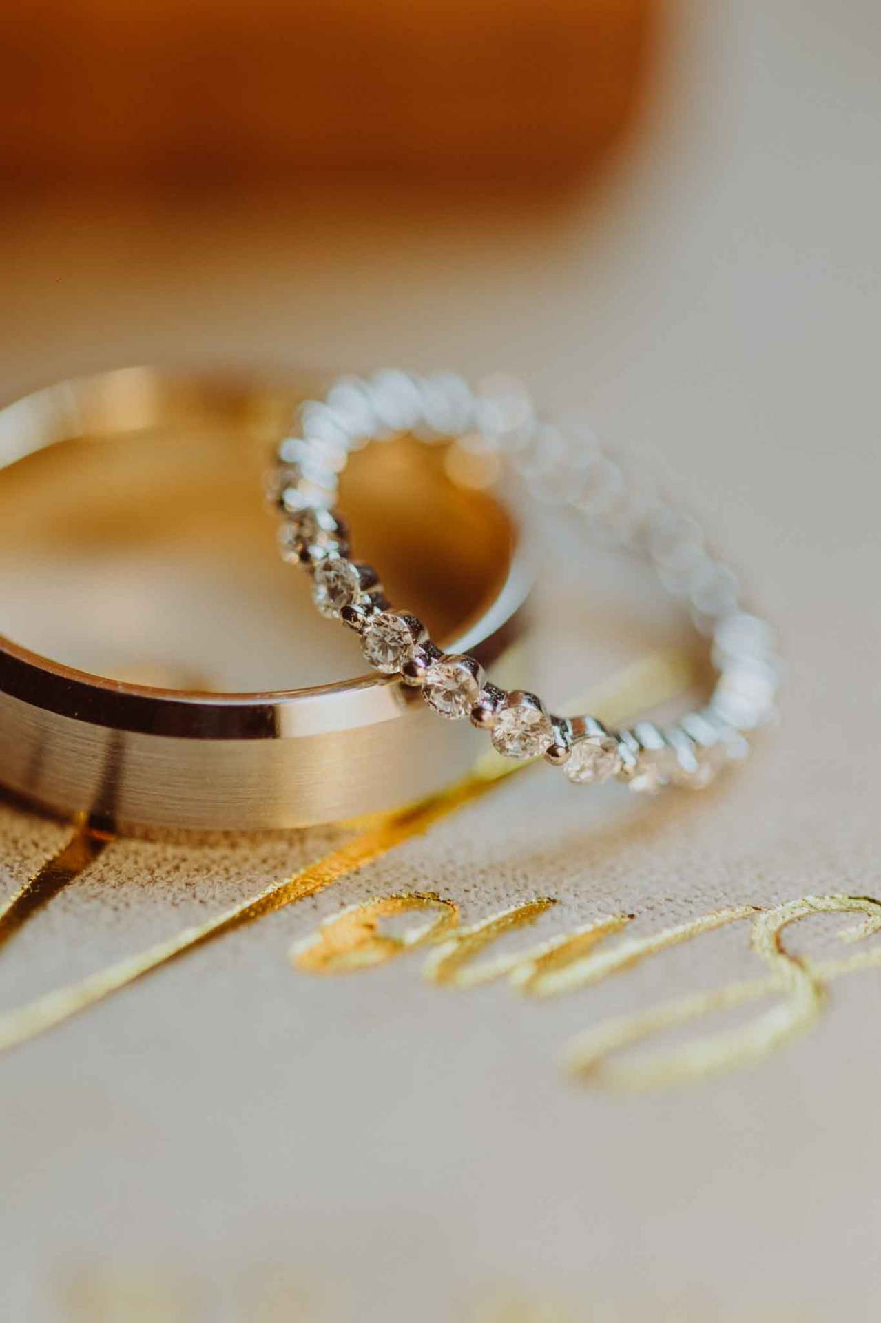 Detalle de anillos de boda sobre invitación con letras doradas