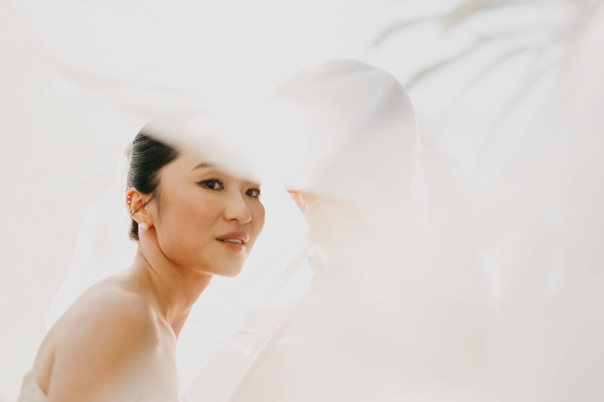 Kara under her veil with soft light creating a dreamy bridal portrait at Xalet del Nin