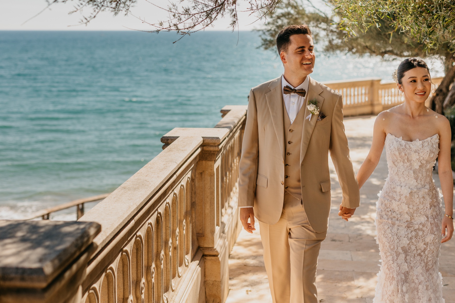 Cameron and Kara walking hand in hand along the seaside promenade at Xalet del Nin