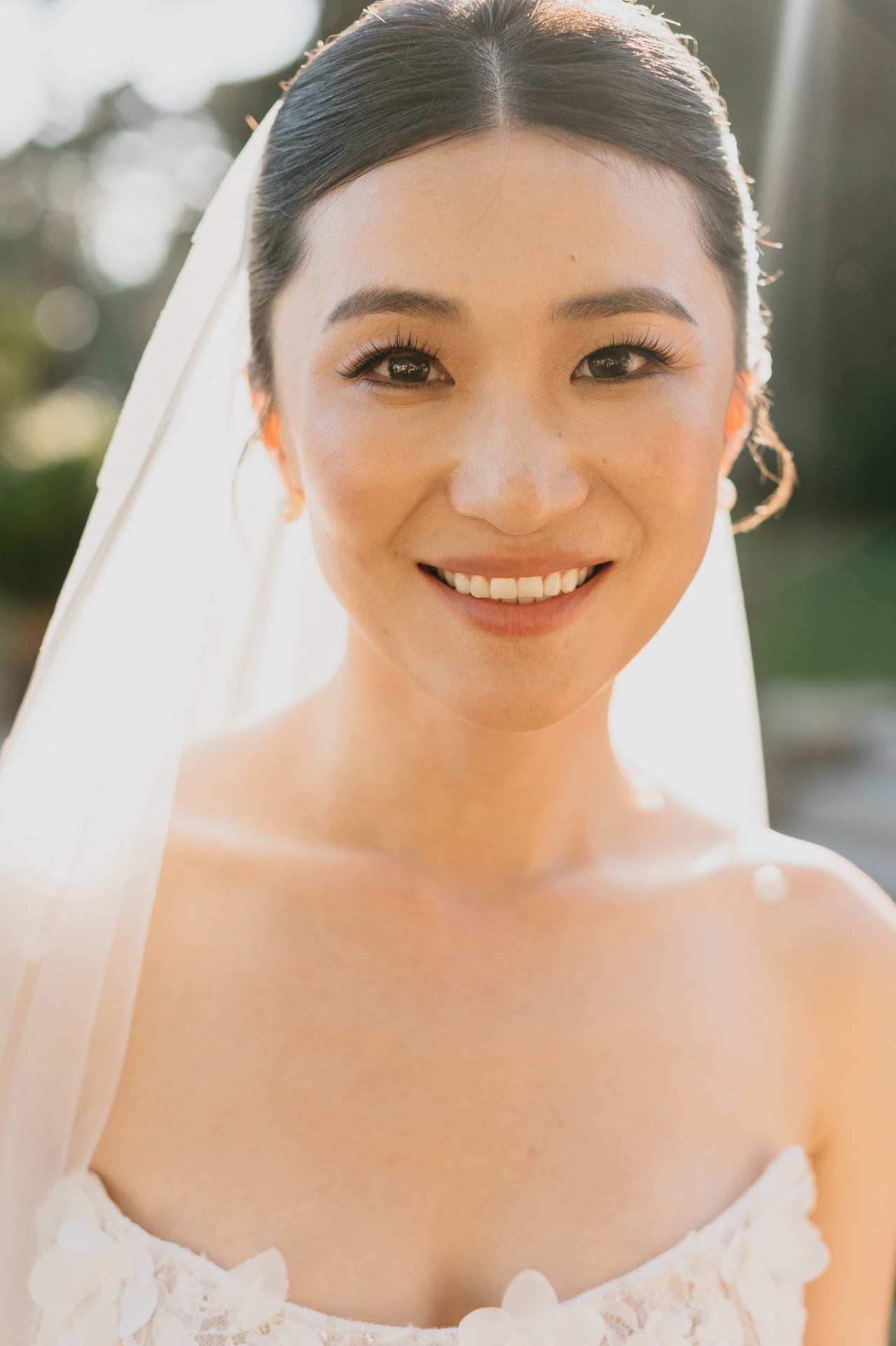 Close-up bridal portrait of Kara smiling radiantly with veil and golden sunlight