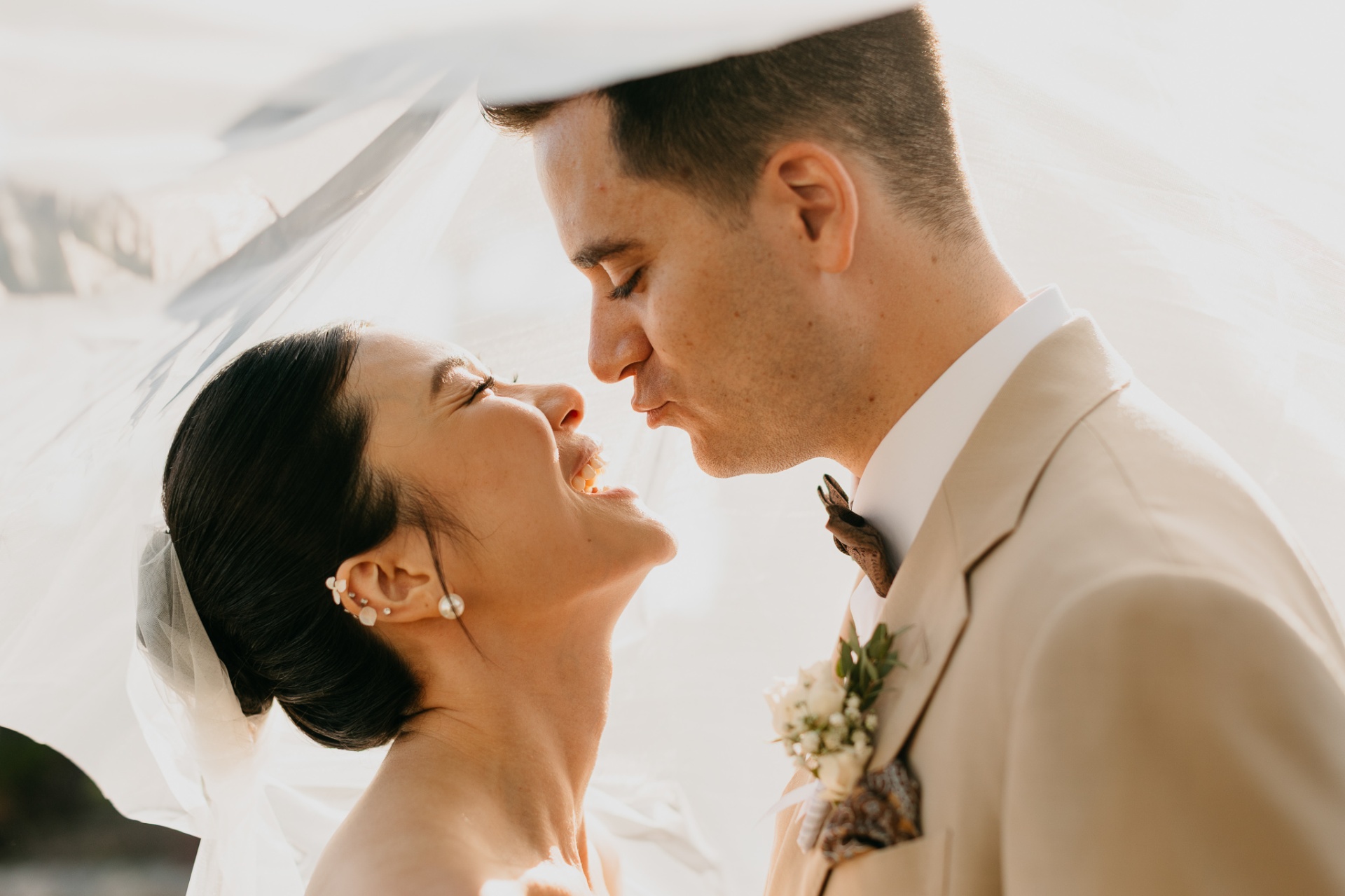 Intimate close-up of Cameron and Kara almost kissing under the bridal veil in golden hour light