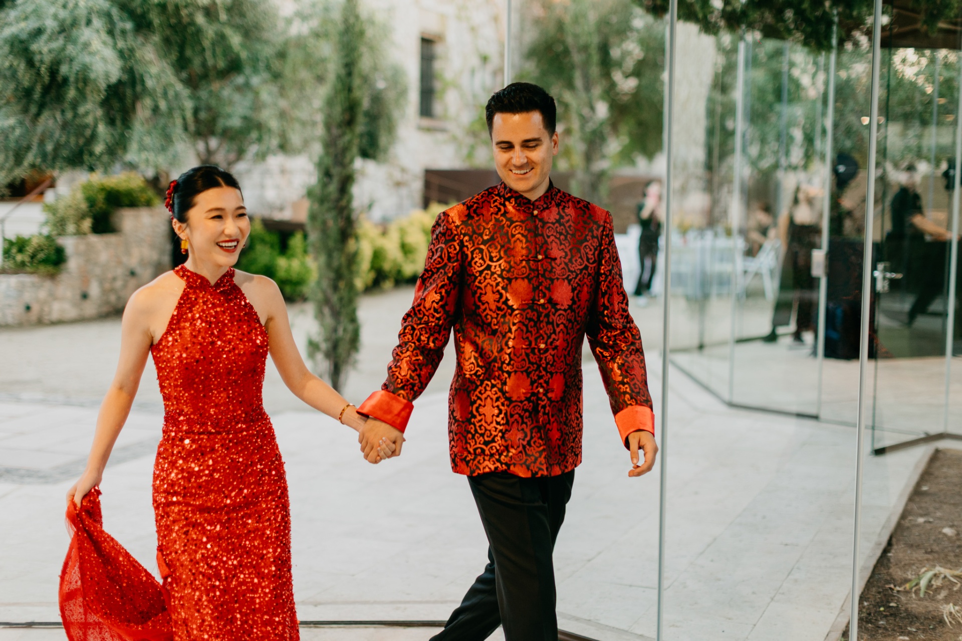 Cameron and Kara in traditional Chinese red wedding attire walking hand in hand at Xalet del Nin