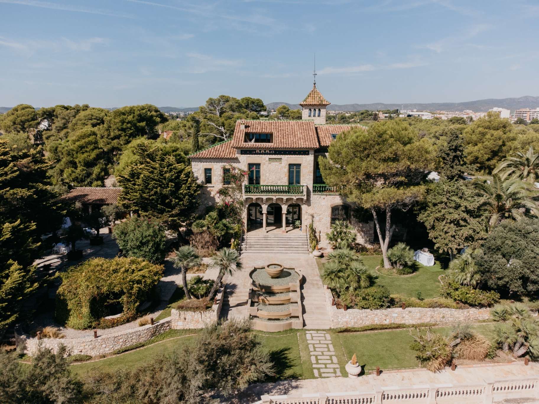 Aerial drone view of the historic Xalet del Nin estate in Sitges with its Moorish arches fountain and lush Mediterranean gardens