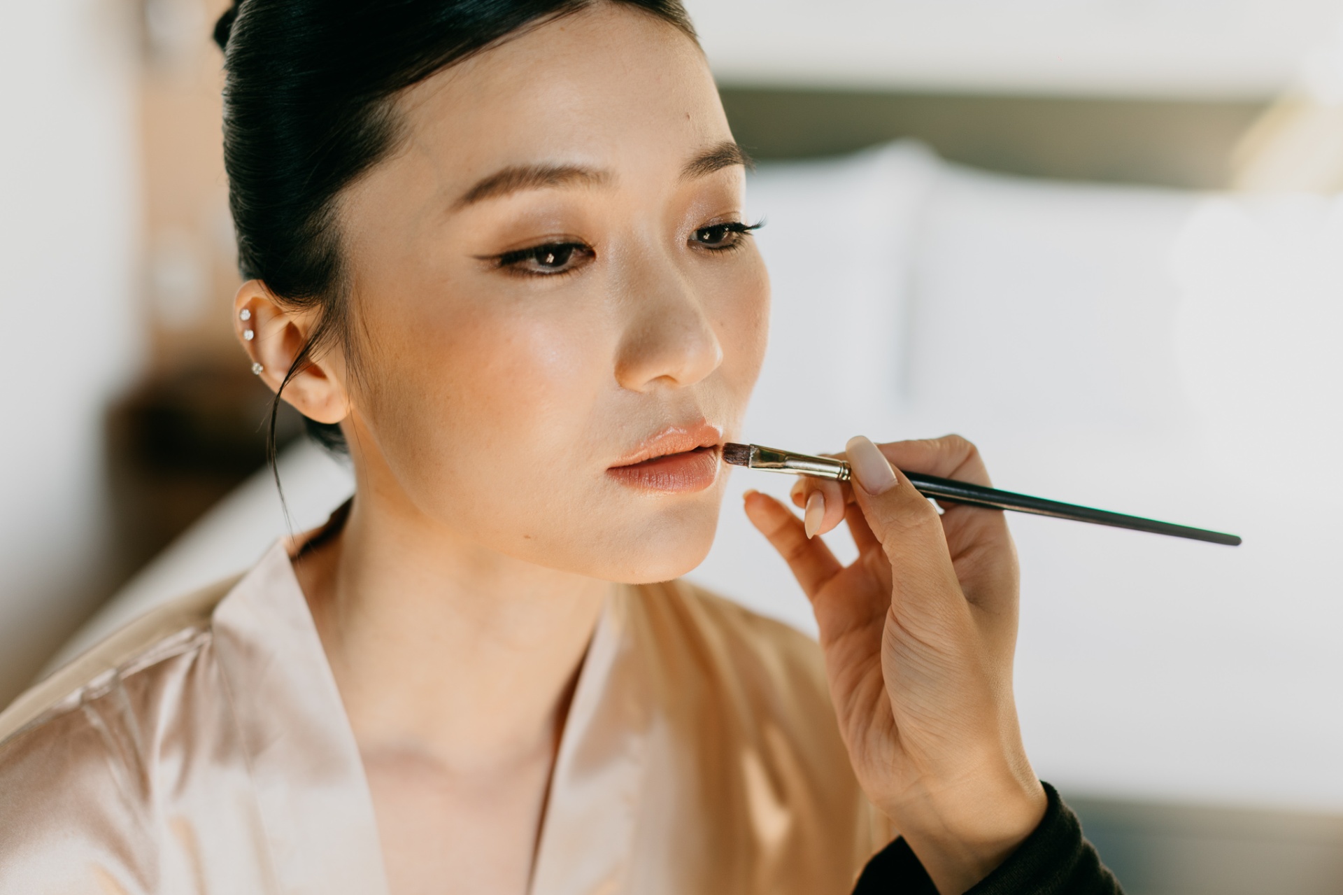 Kara having her makeup done with a lip brush in soft natural light