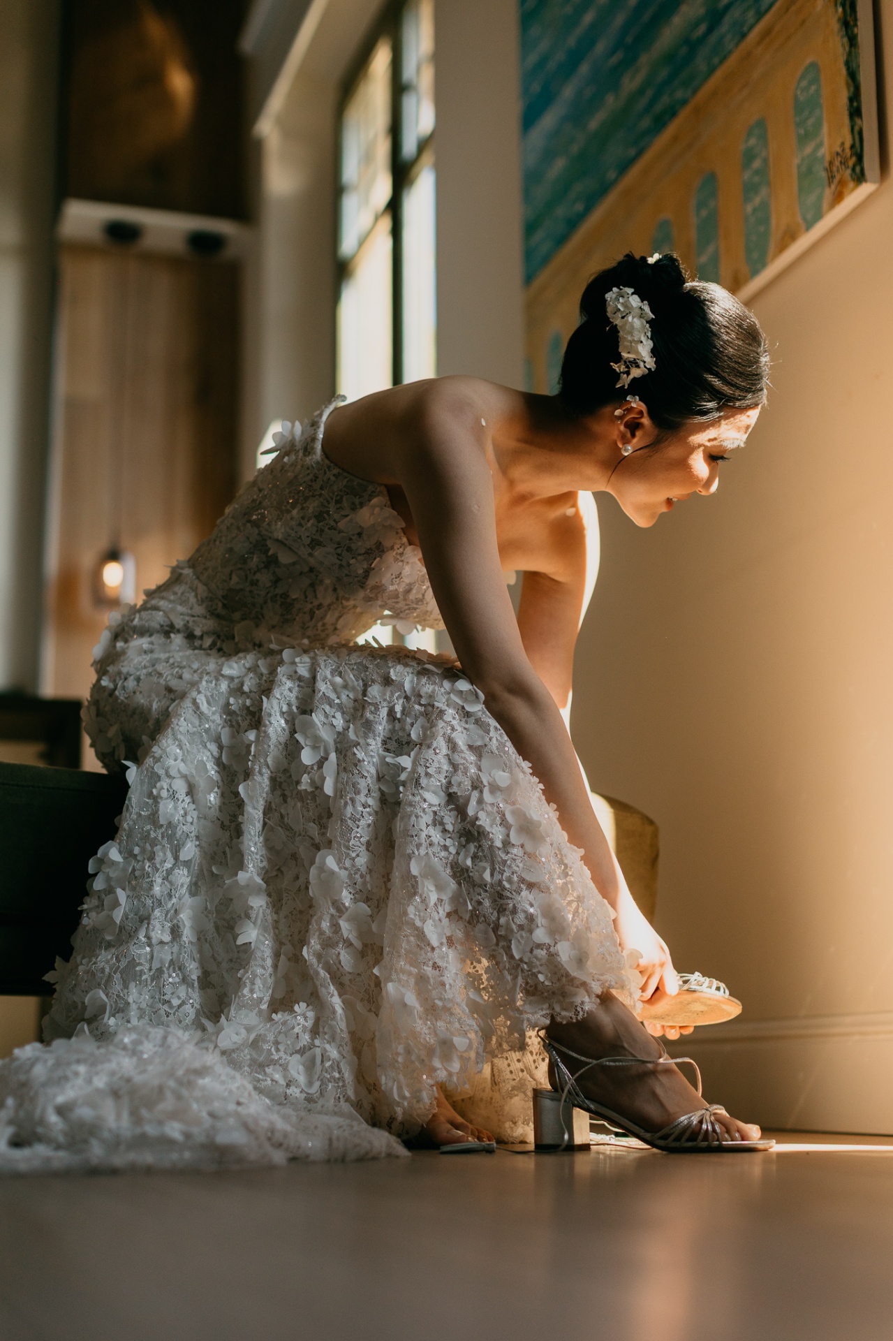 Kara sitting down to put on her wedding shoes in her detailed floral lace dress