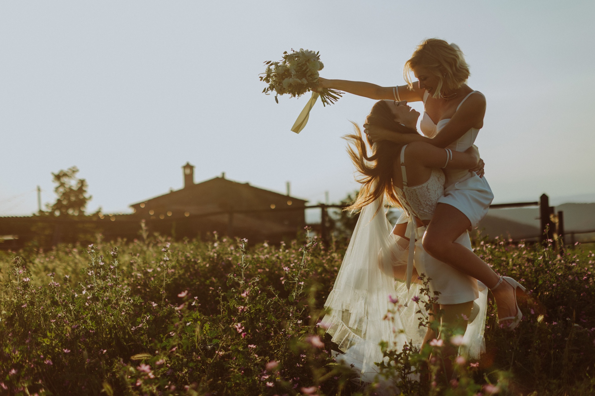 Bride lifting partner in wildflower field at sunset at TMBTP