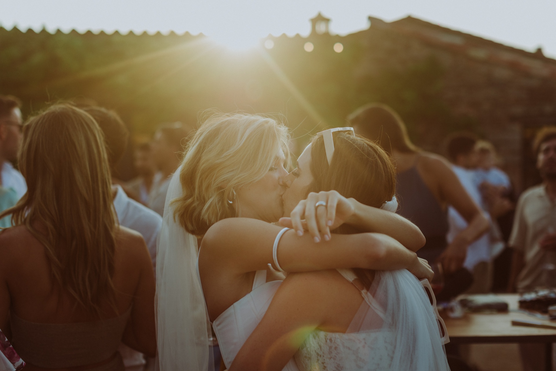 Brides kissing at sunset with golden lens flare at TMBTP