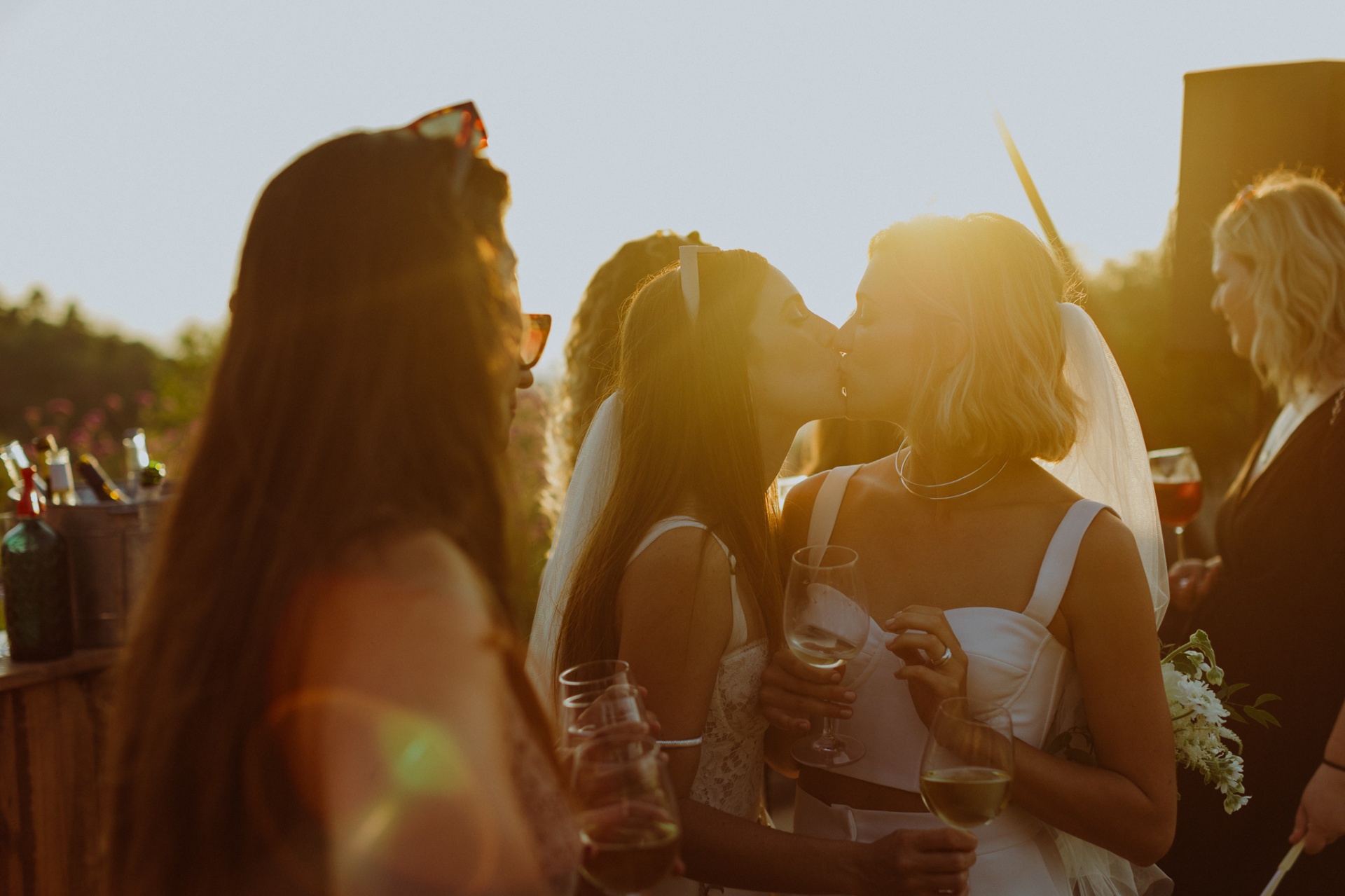 Intimate kiss between brides during golden hour cocktails