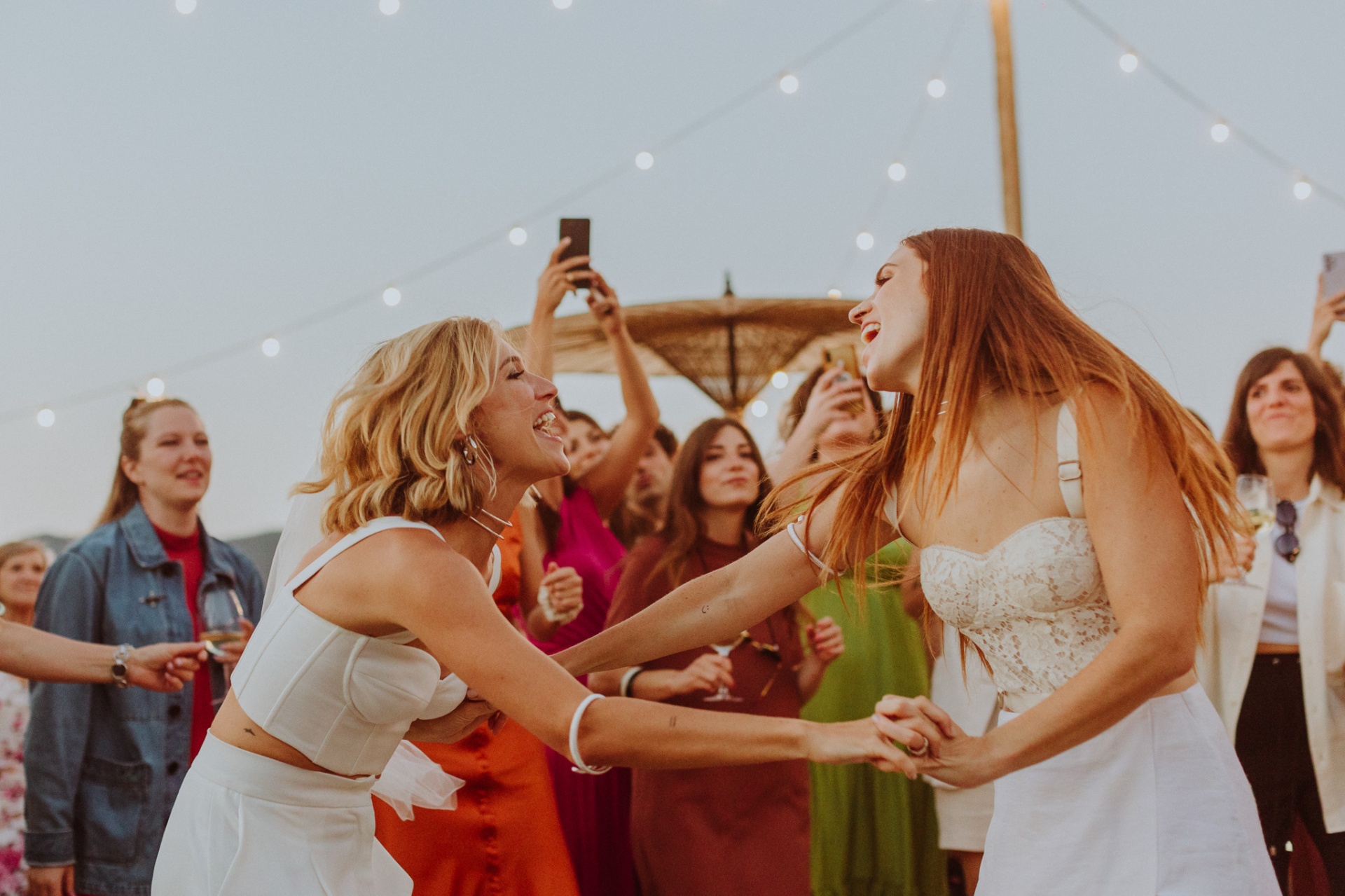 Chiara and Ro dancing together under string lights at reception