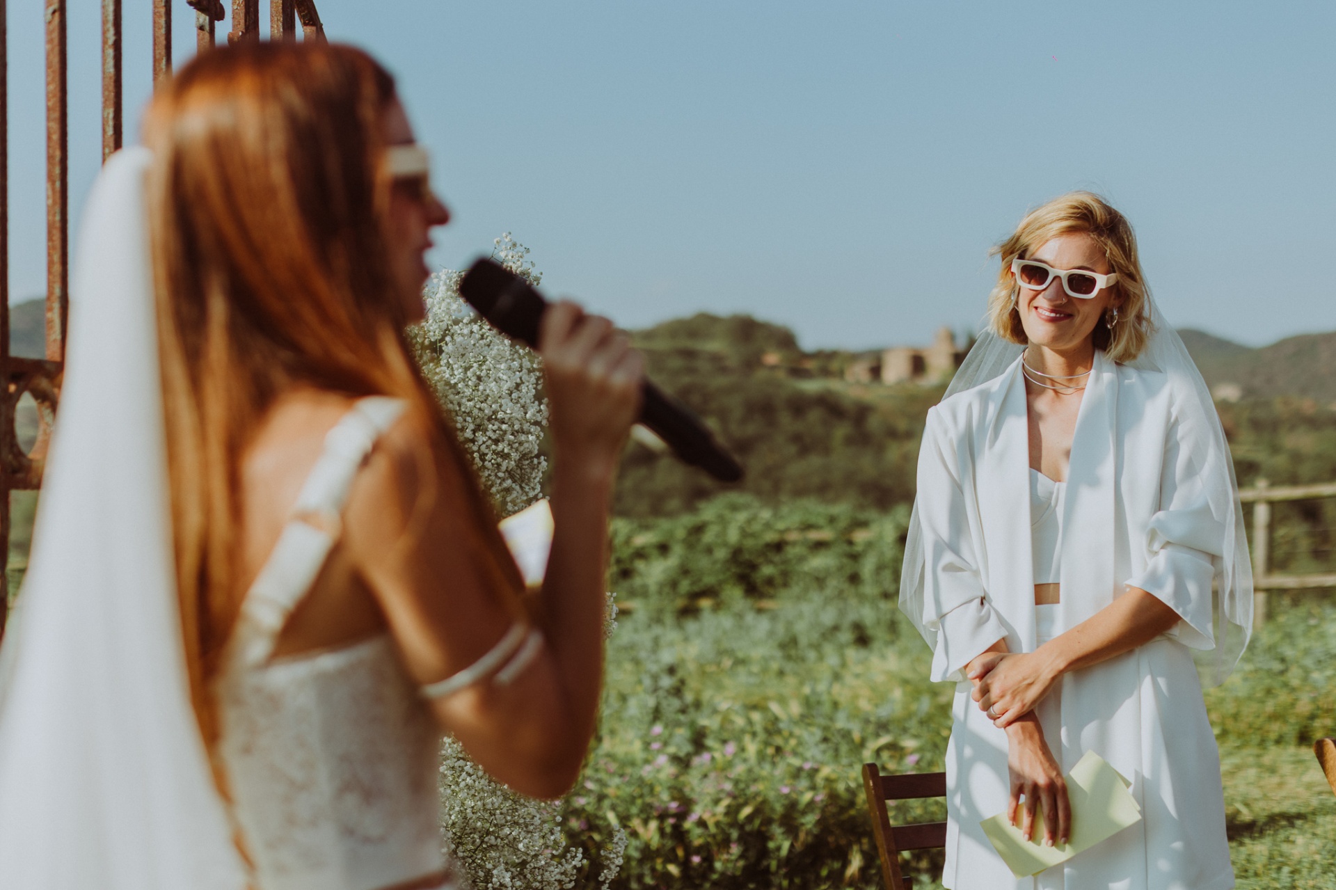 Ro reading vows while Chiara watches with joy at outdoor ceremony