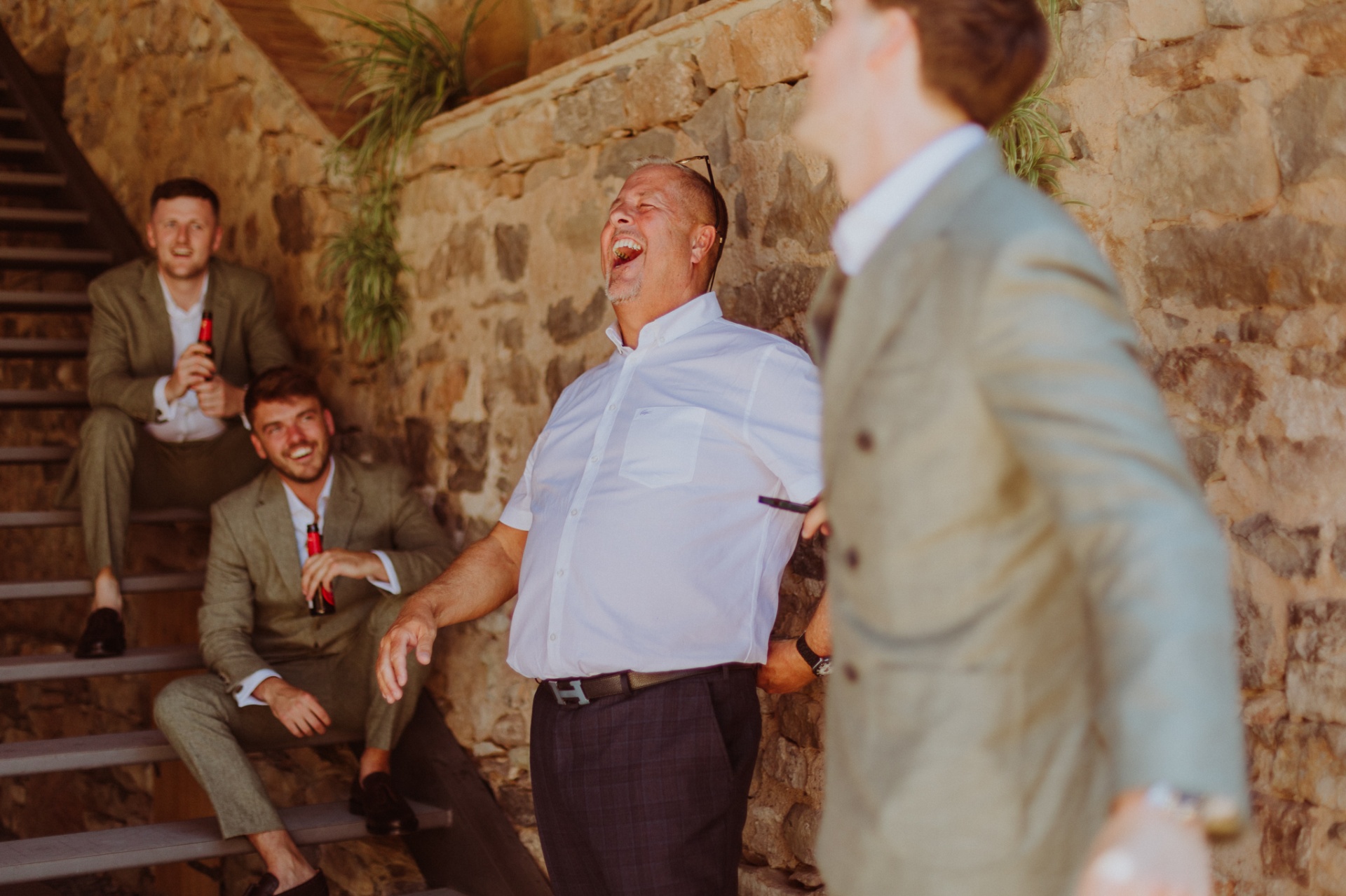Groomsmen laughing on stone steps during cocktail hour at TMBTP
