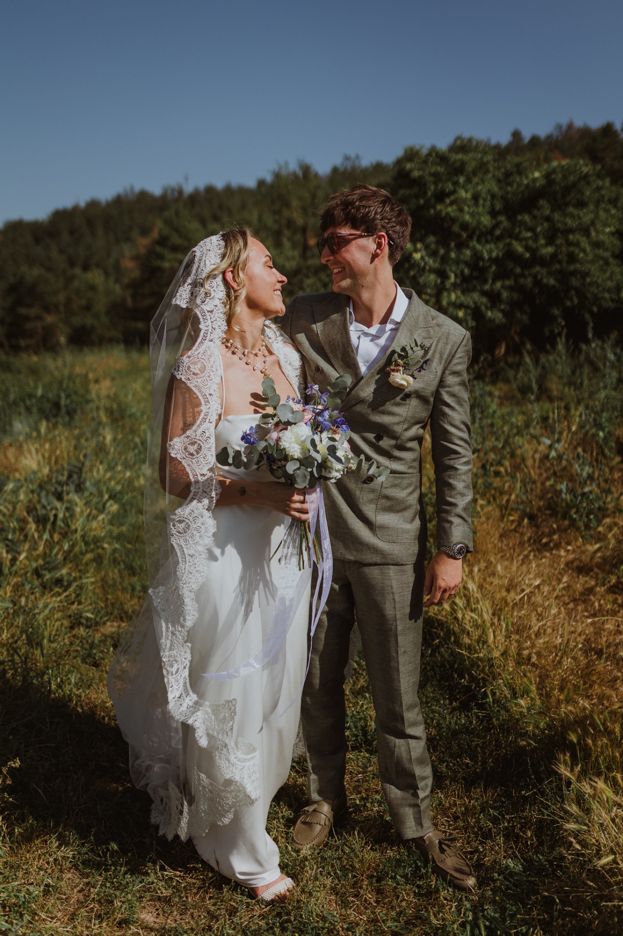 Ellie and Conor smiling with bouquet and lace veil in golden sunlight