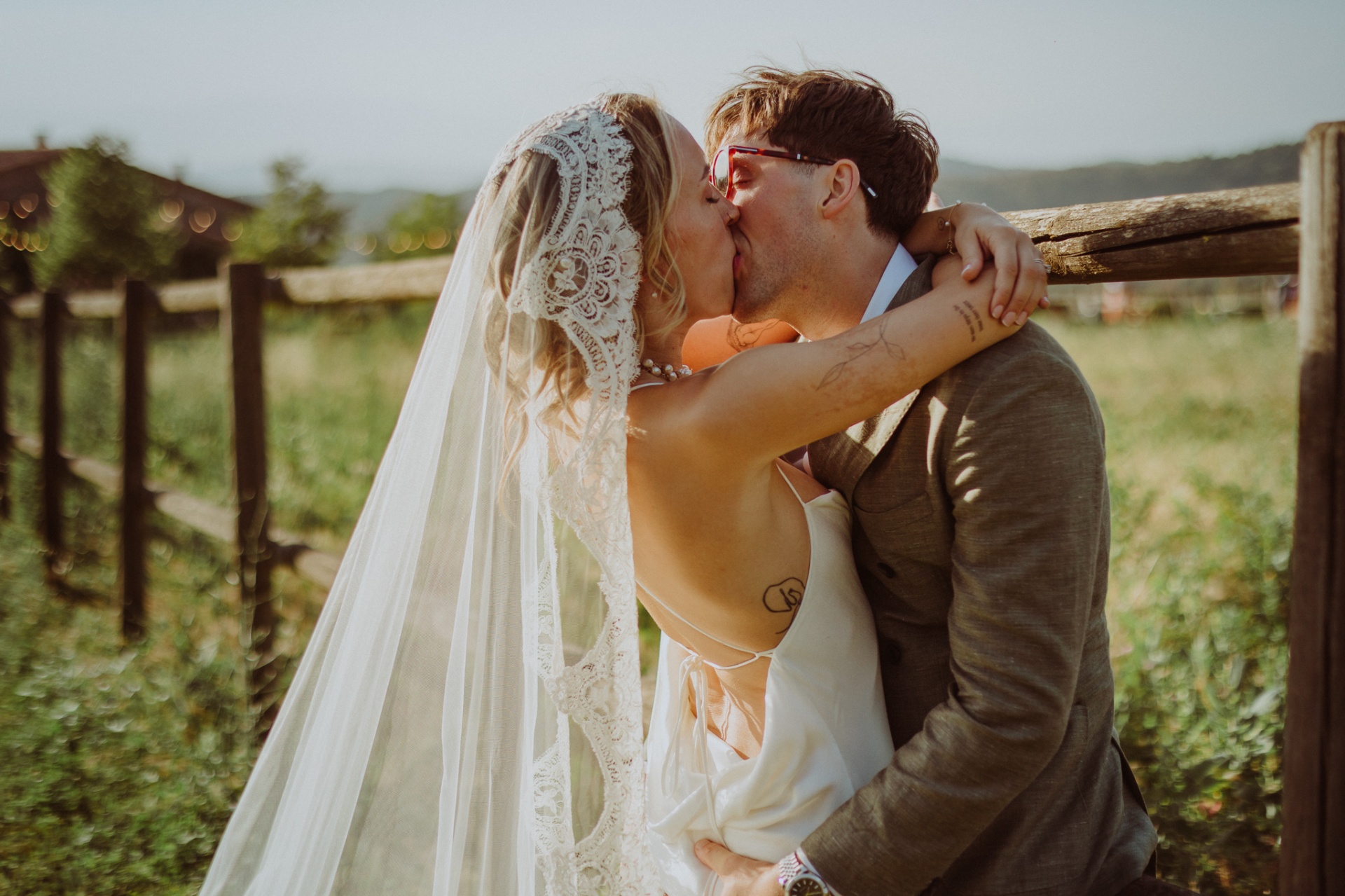 Ellie and Conor kissing passionately by wooden fence at golden hour
