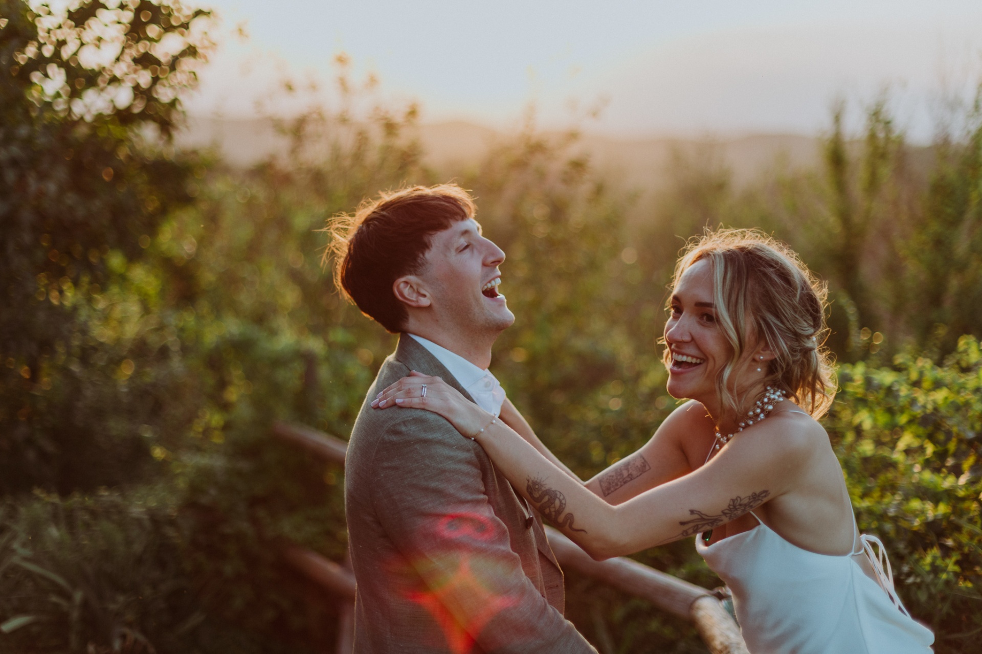 Ellie and Conor laughing together with golden sunset light and lens flare