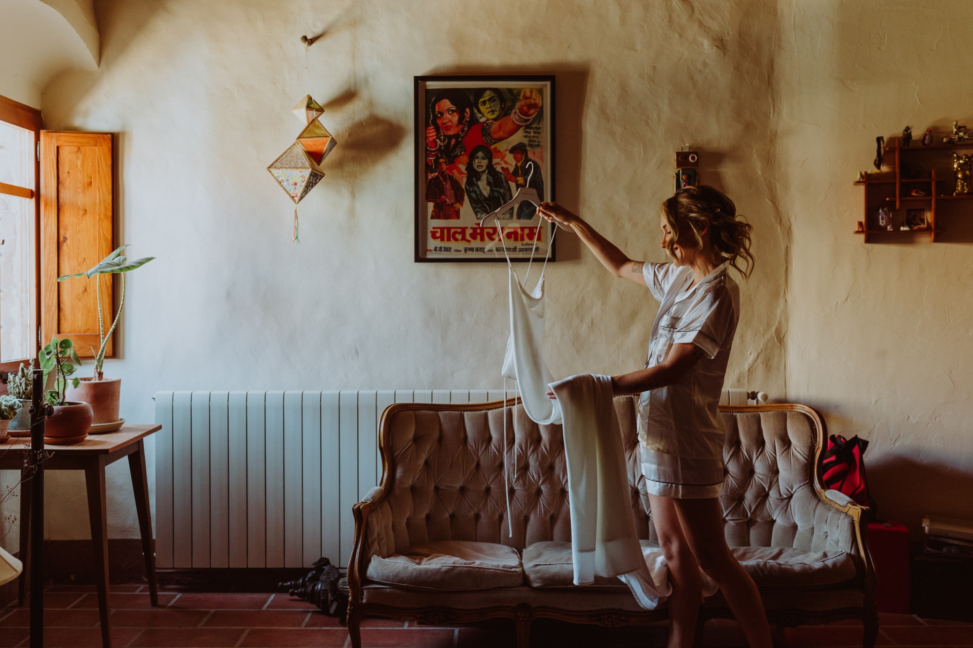 Ellie holding her wedding dress in rustic room at This Must Be The Place