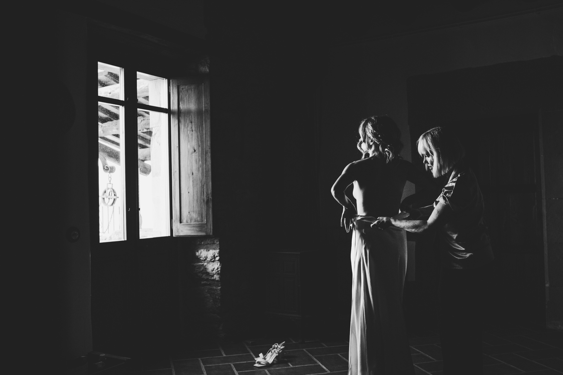 Mother helping bride into dress in dramatic black and white at TMBTP