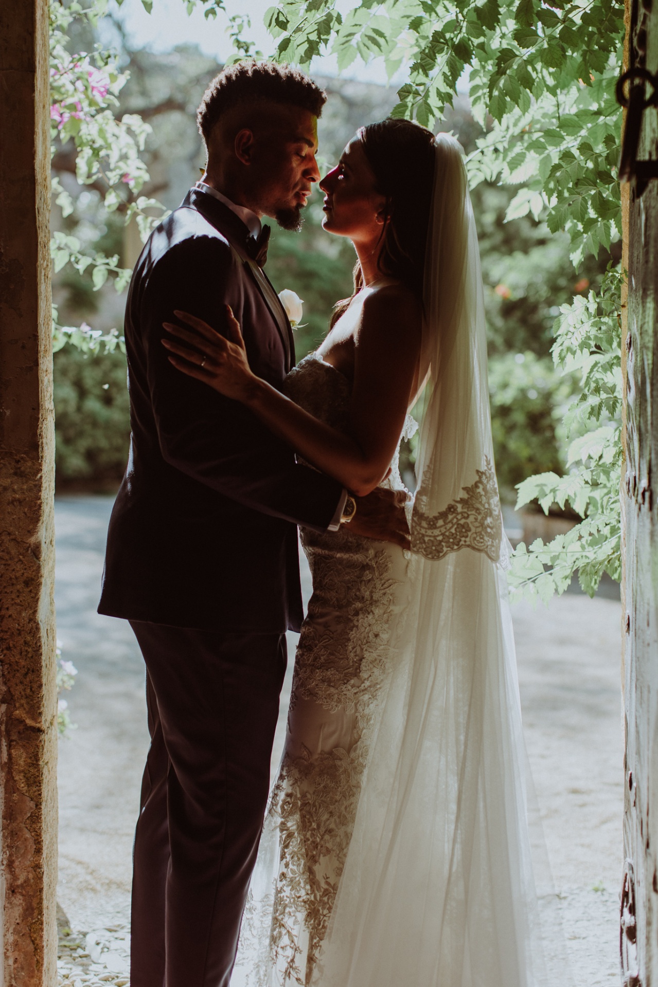 Laura and Jose in silhouette embrace framed by doorway and garden light