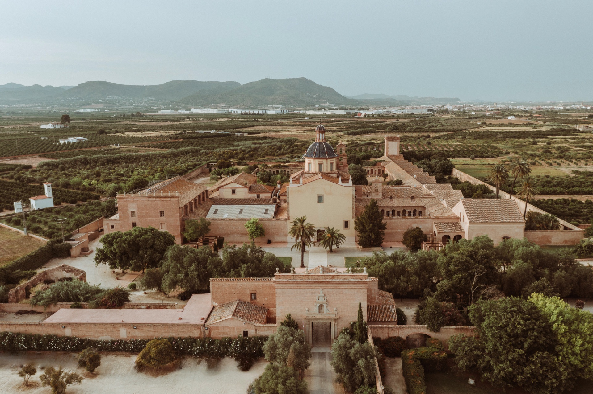 Vista aérea de La Cartuja de Ara Christi con su cúpula azul rodeada de campos valencianos al atardecer