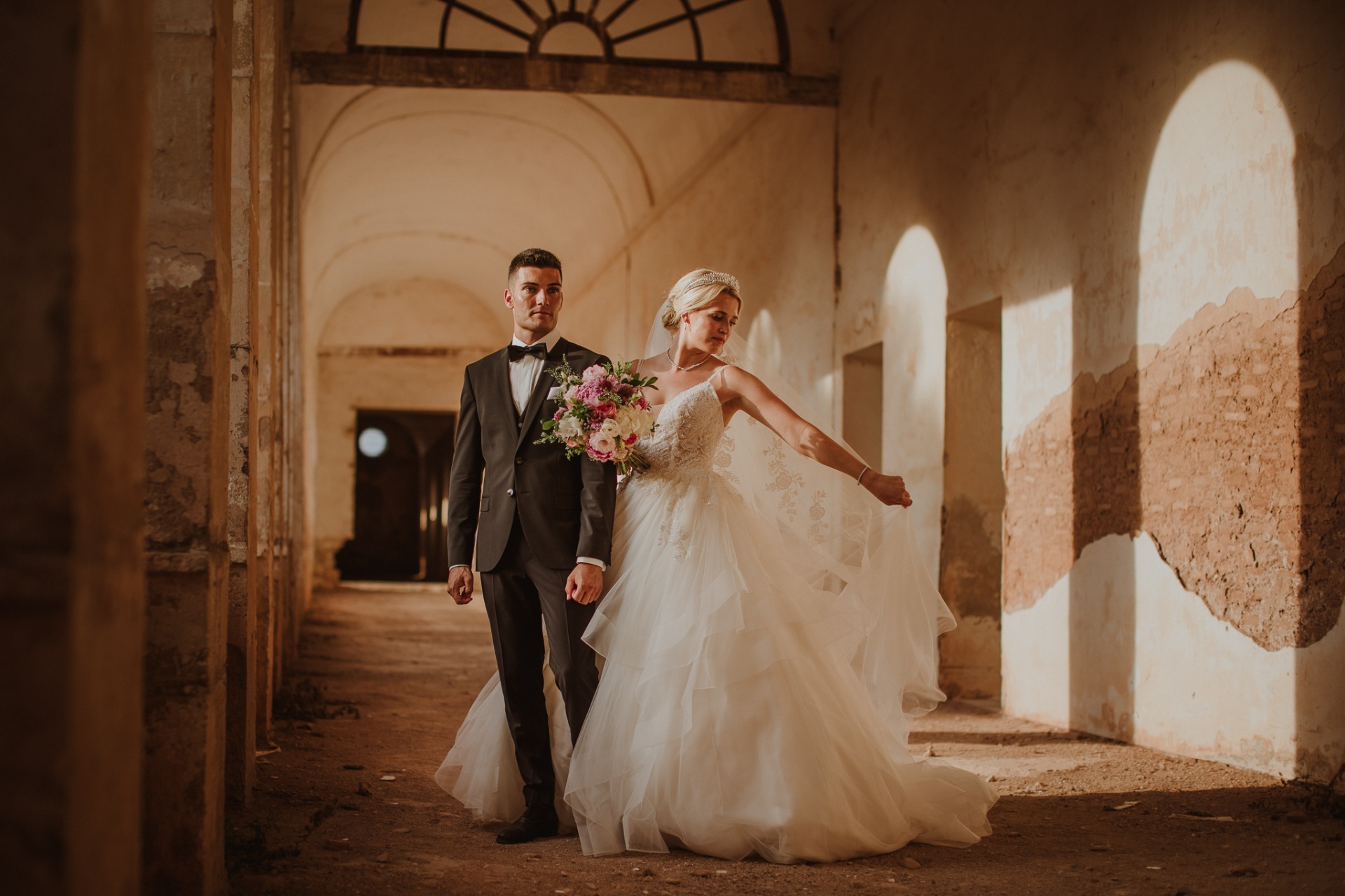 Michelle y Jorge caminando por el claustro antiguo de La Cartuja con claroscuros y ventanales