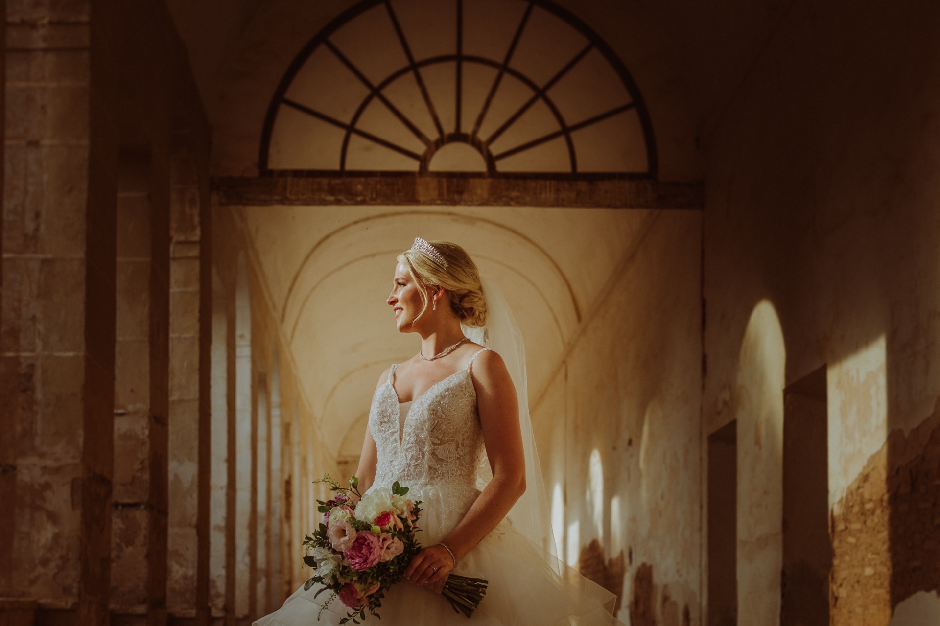 Retrato de Michelle con su ramo de peonías bajo el arco de medio punto del claustro con luz dorada