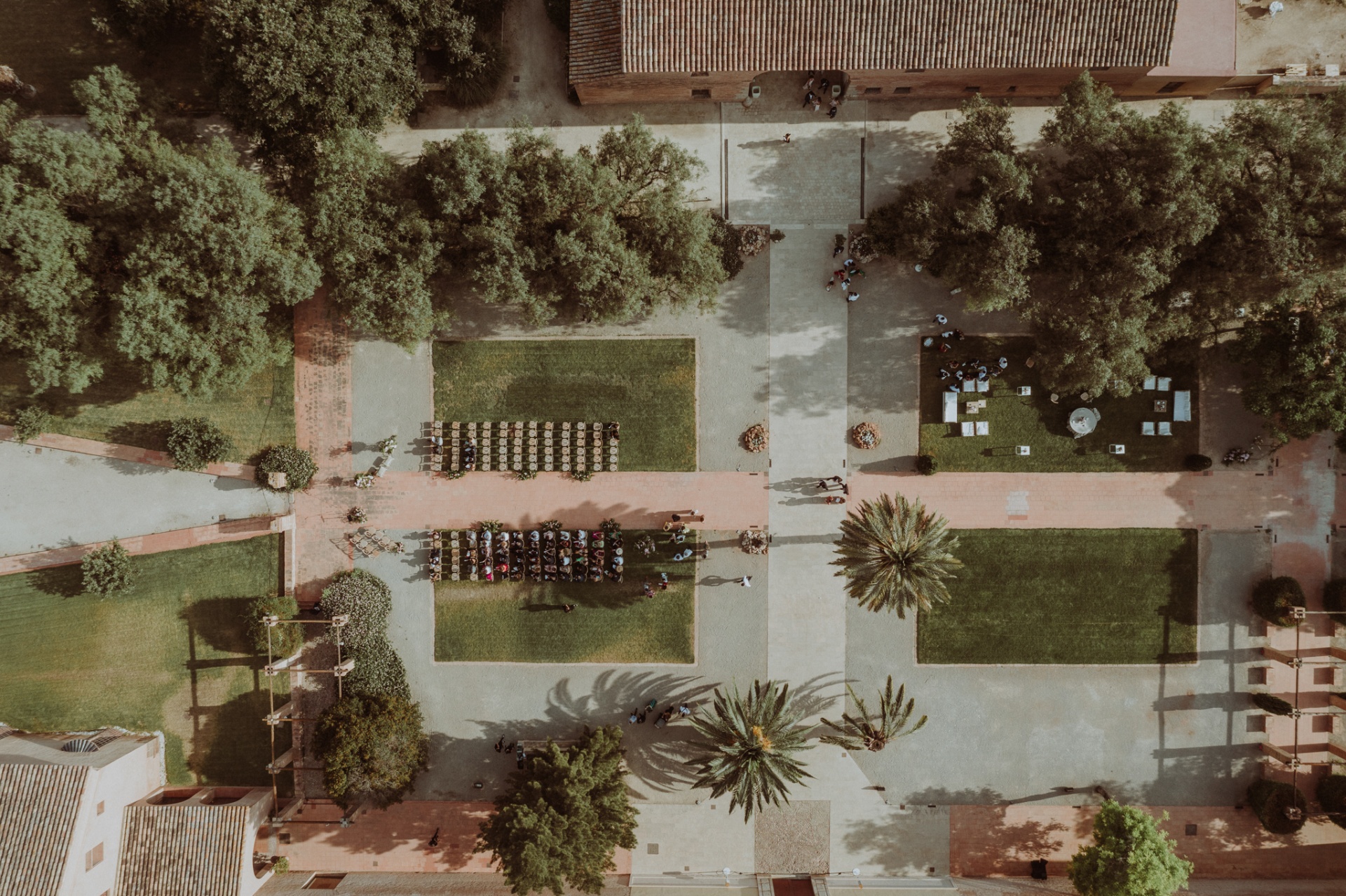 Vista aérea cenital de la ceremonia al aire libre en los jardines de La Cartuja de Ara Christi con palmeras y sillas crossback