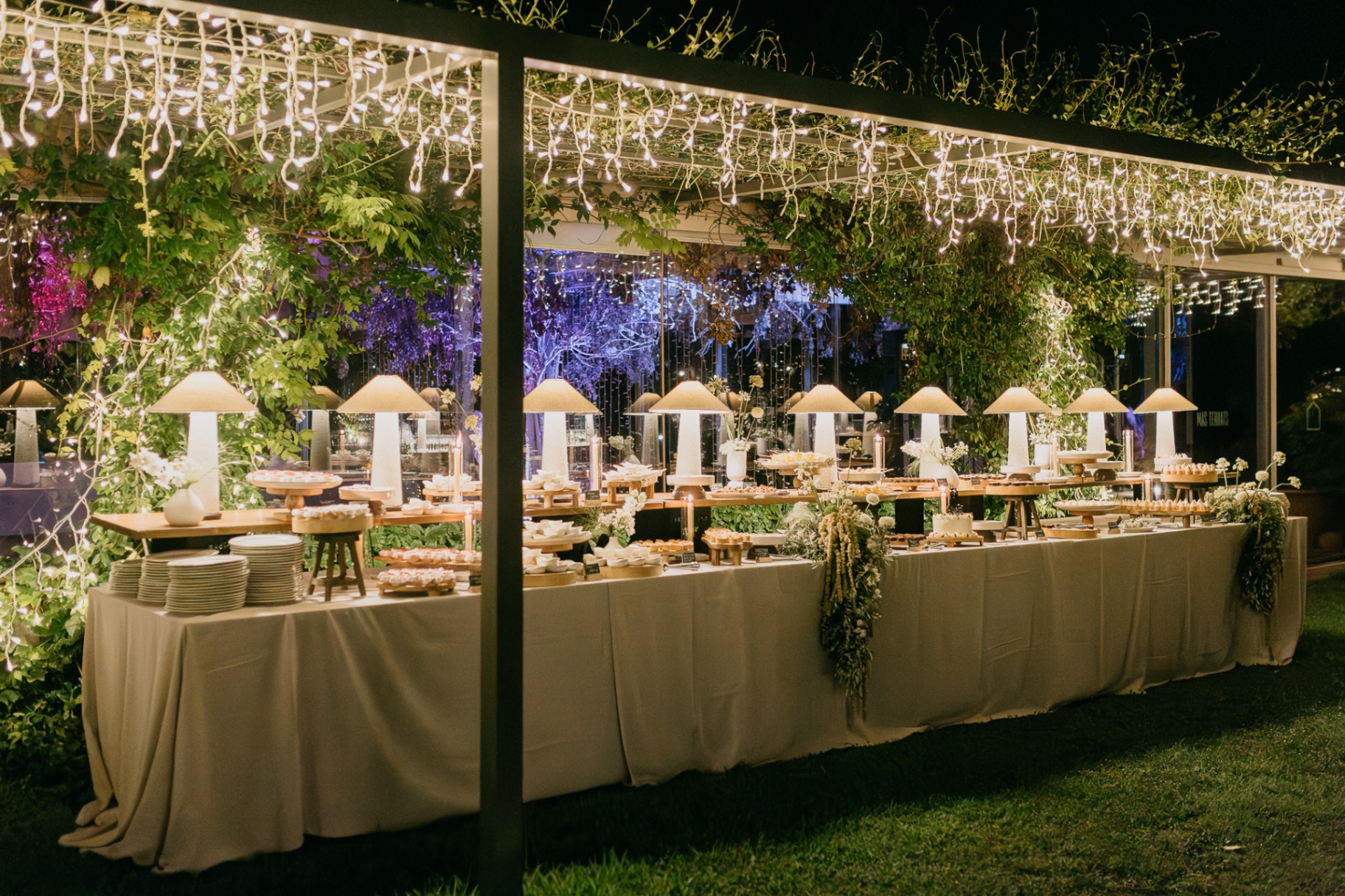 Dessert buffet table with fairy lights and greenery at Mas Terrats